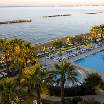 lots of sun beds around pool next to a beach